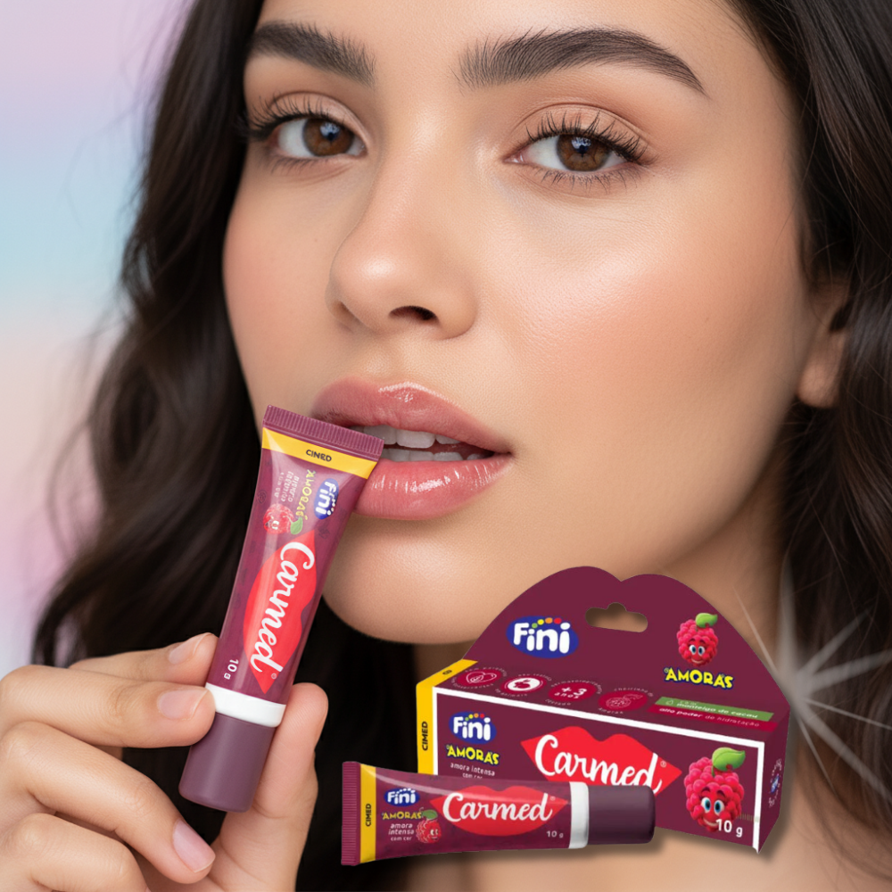 A woman holds a tube of Carmed Fini Amora Intensa raspberry lip balm, showcasing its vibrant packaging.