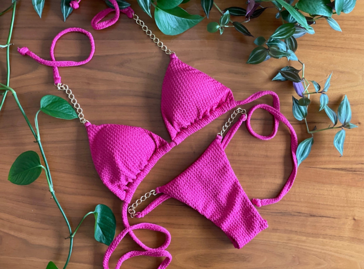 The bikini features a triangle top with tie sides and a Brazilian-cut bottom, also with tie sides.