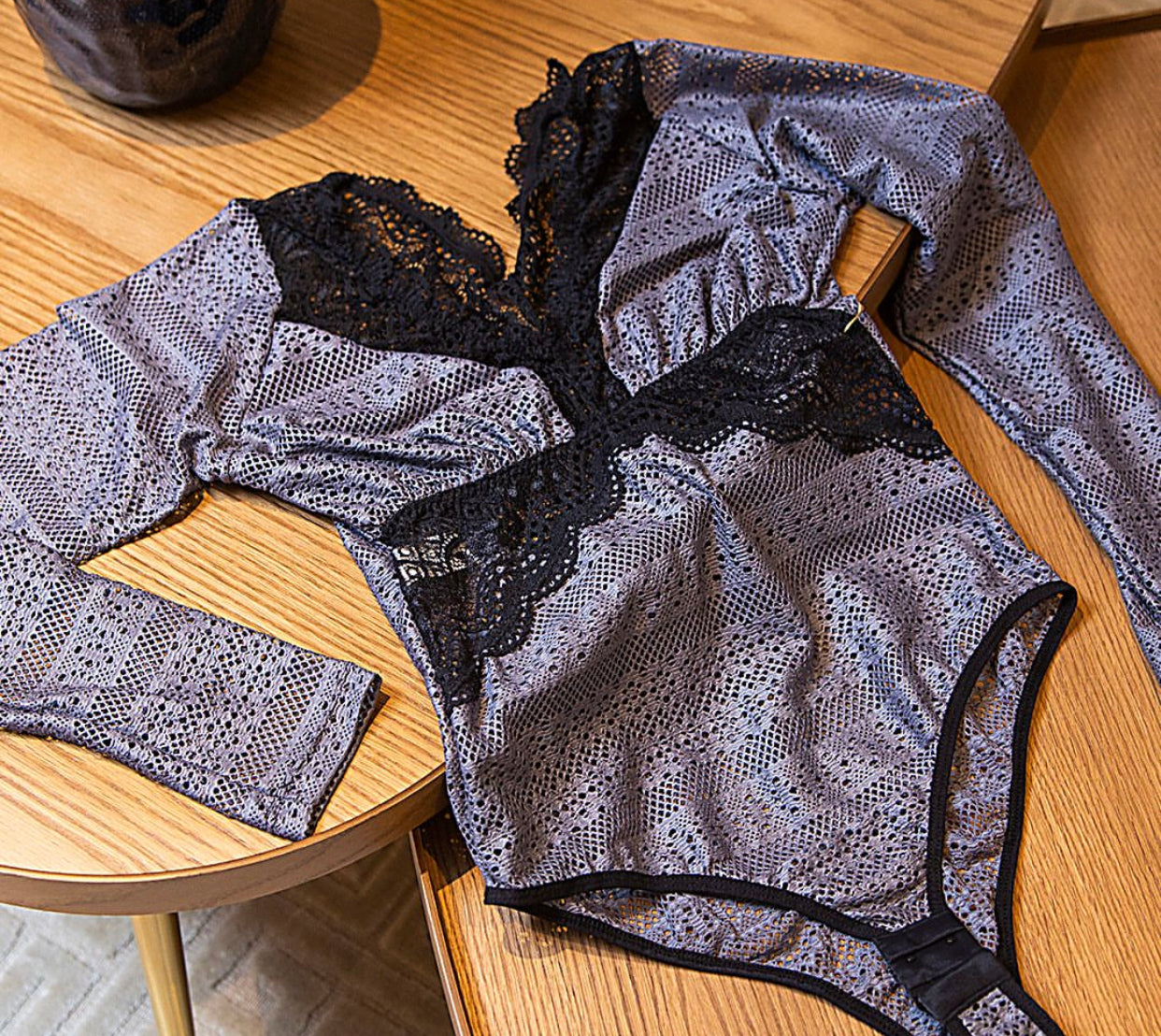 V-neckline with black lace detailing and a grey or silver patterned material on the body and sleeves in Body Sensations.