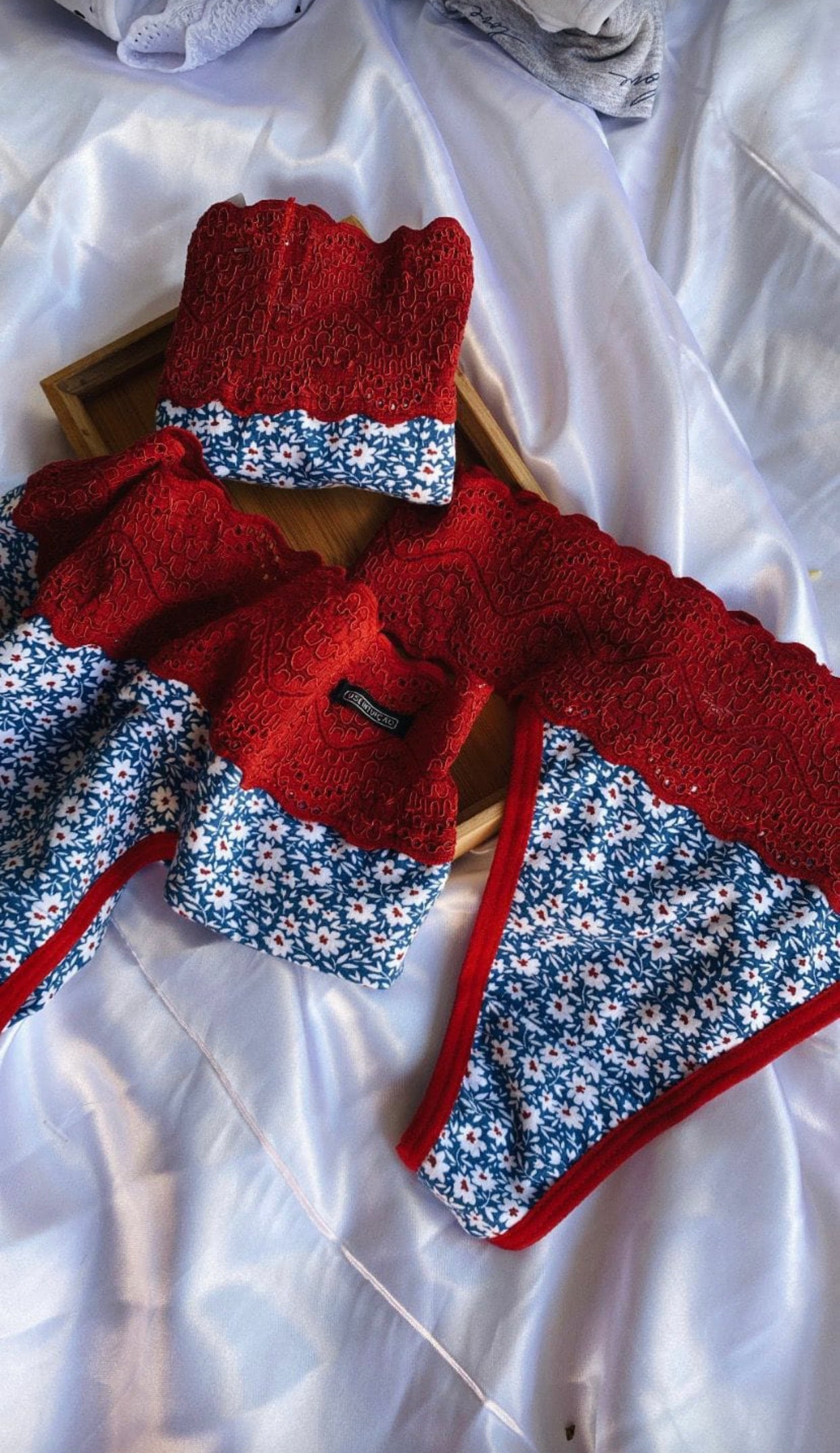 Pair of red, knit, double-string style underwear with blue and white floral trim.