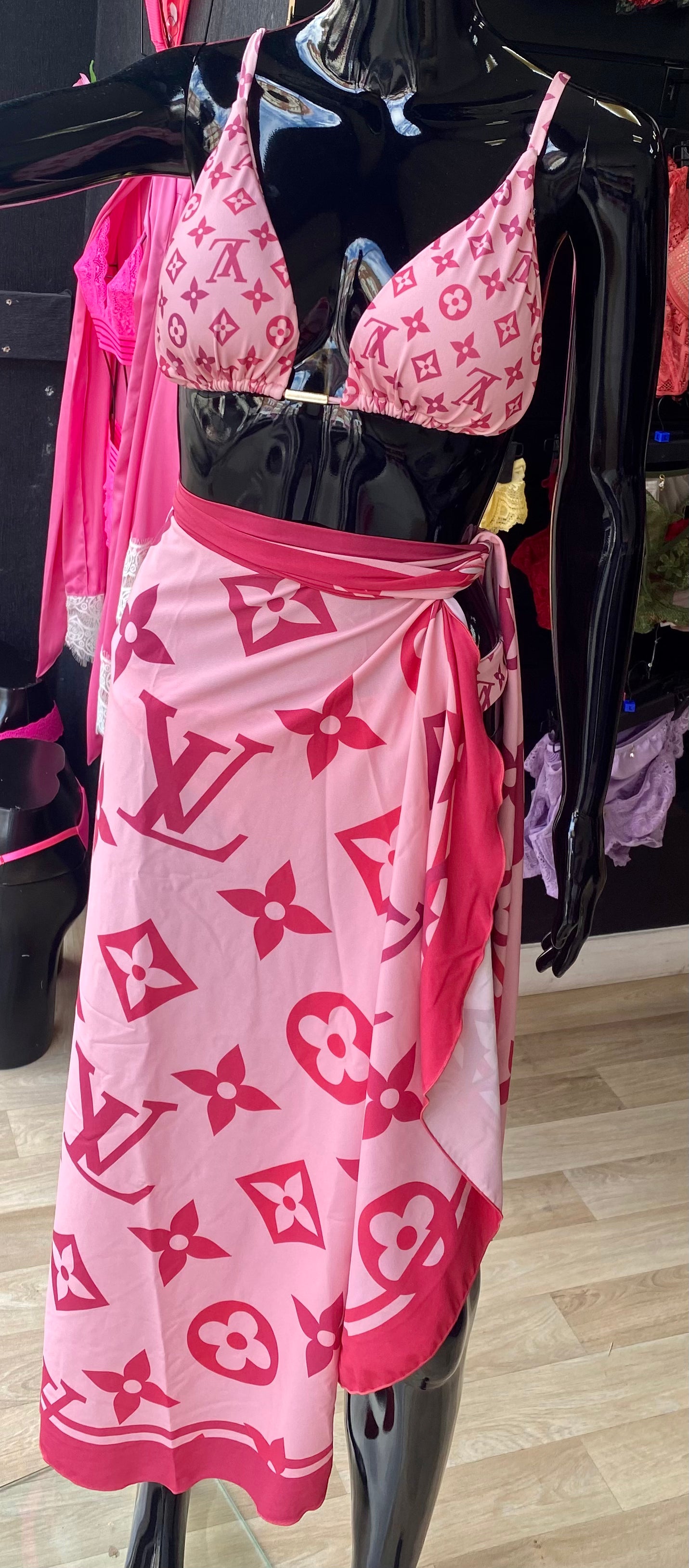 A pink bikini set with the initials LV on the pattern, displayed on a mannequin.