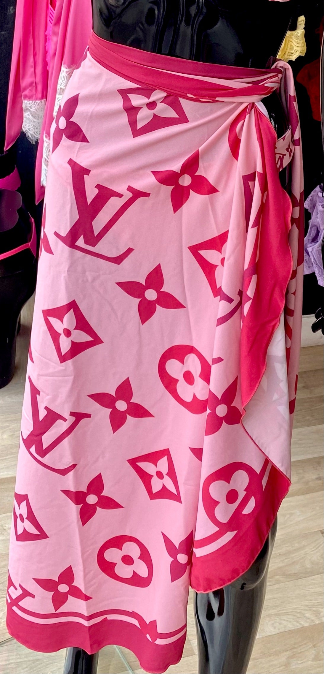 A pink beach cover-up with geometric patterns including hearts and stars, displayed on a mannequin.