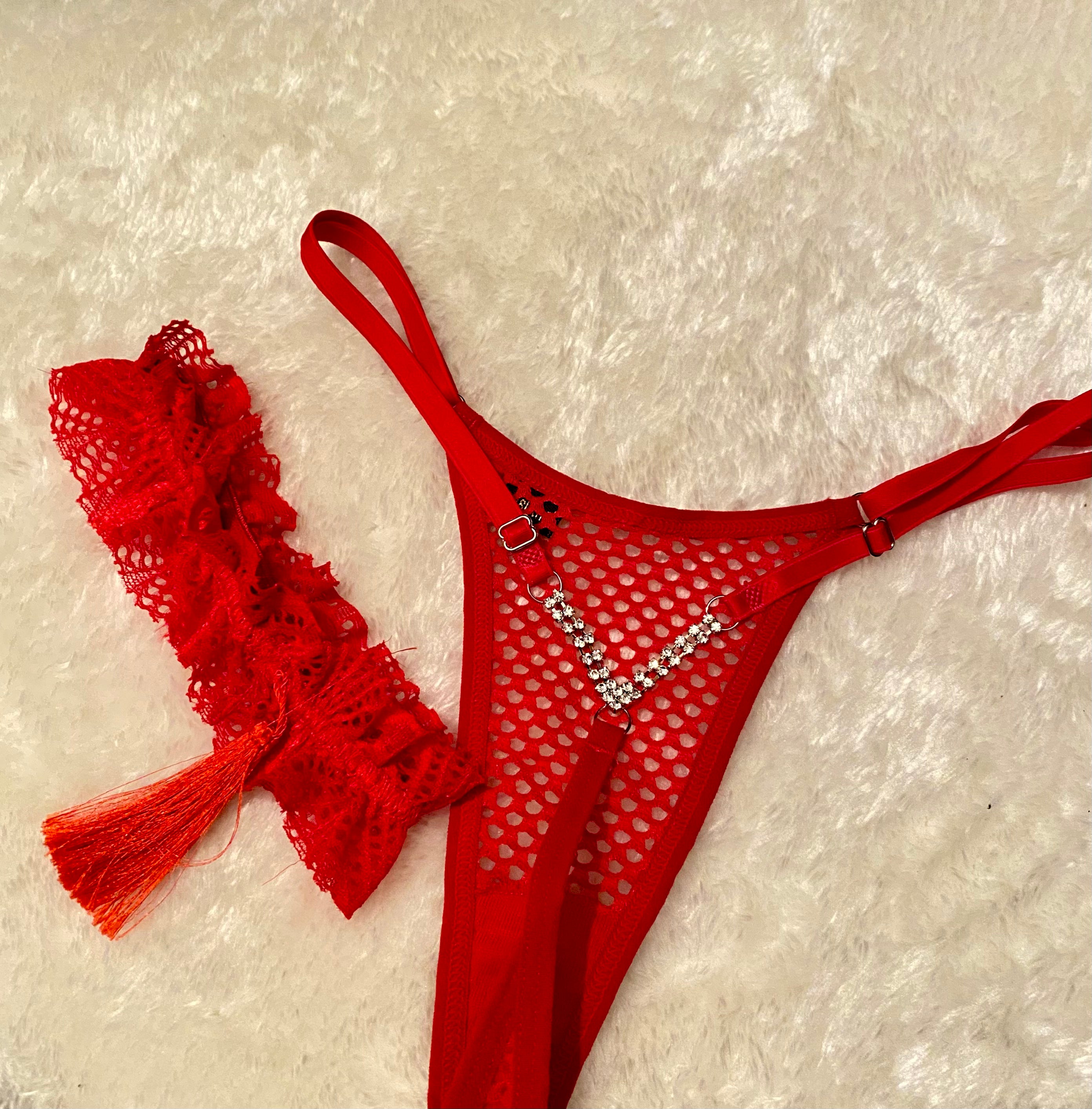 A red panty and leggings set with a lace pattern, accompanied by a red beret with a feather, displayed on a fluffy white surface.